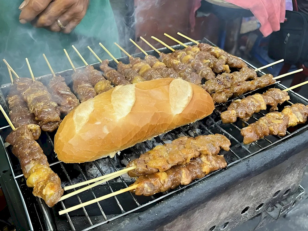 Món bò nướng Campuchia thơm lừng với thịt bò ướp sả, tỏi đậm vị, nướng tí tách trên than hồng, hương thơm khắp cả dãy phố